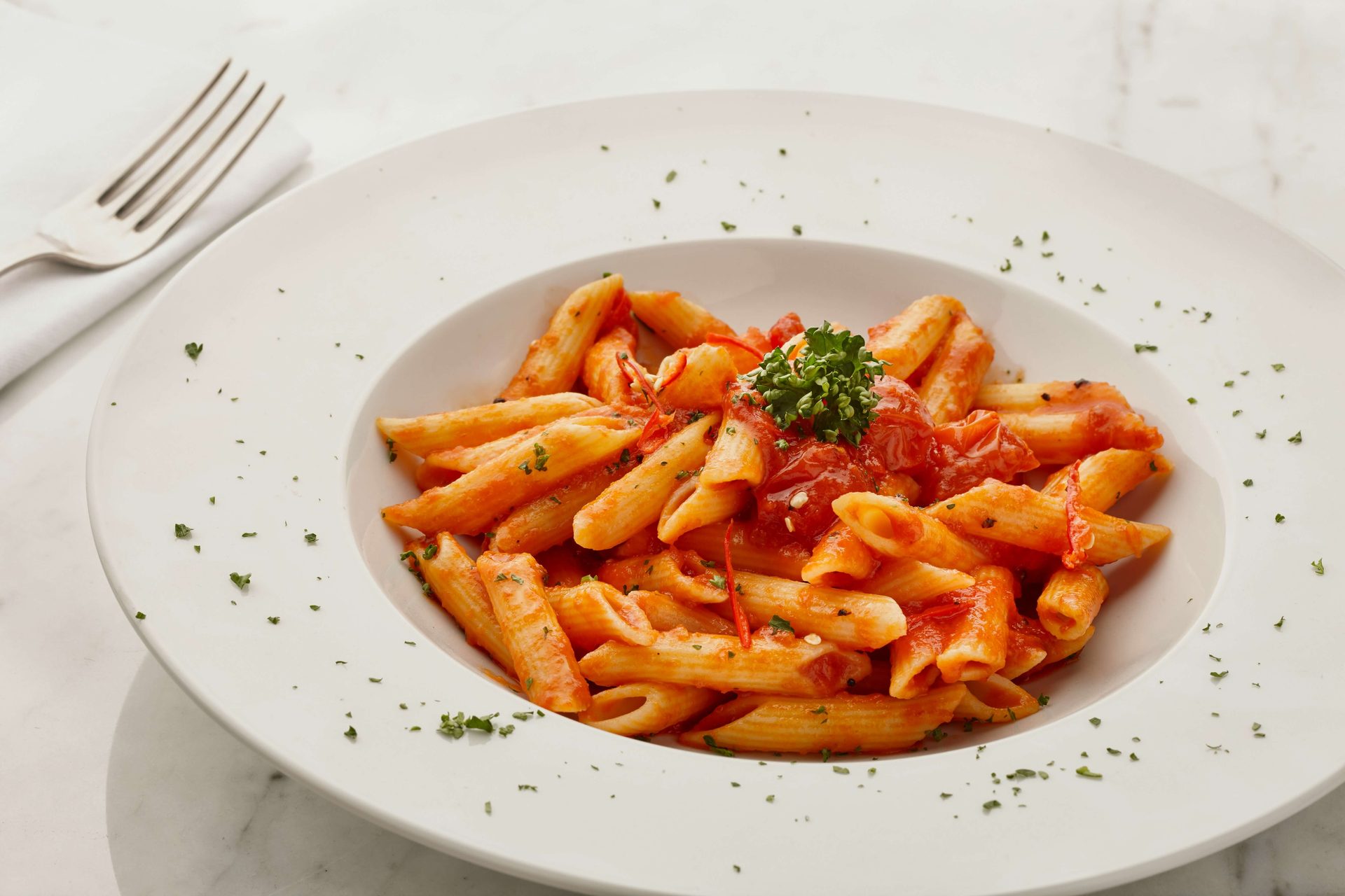 A plate of penne pasta with tomato sauce